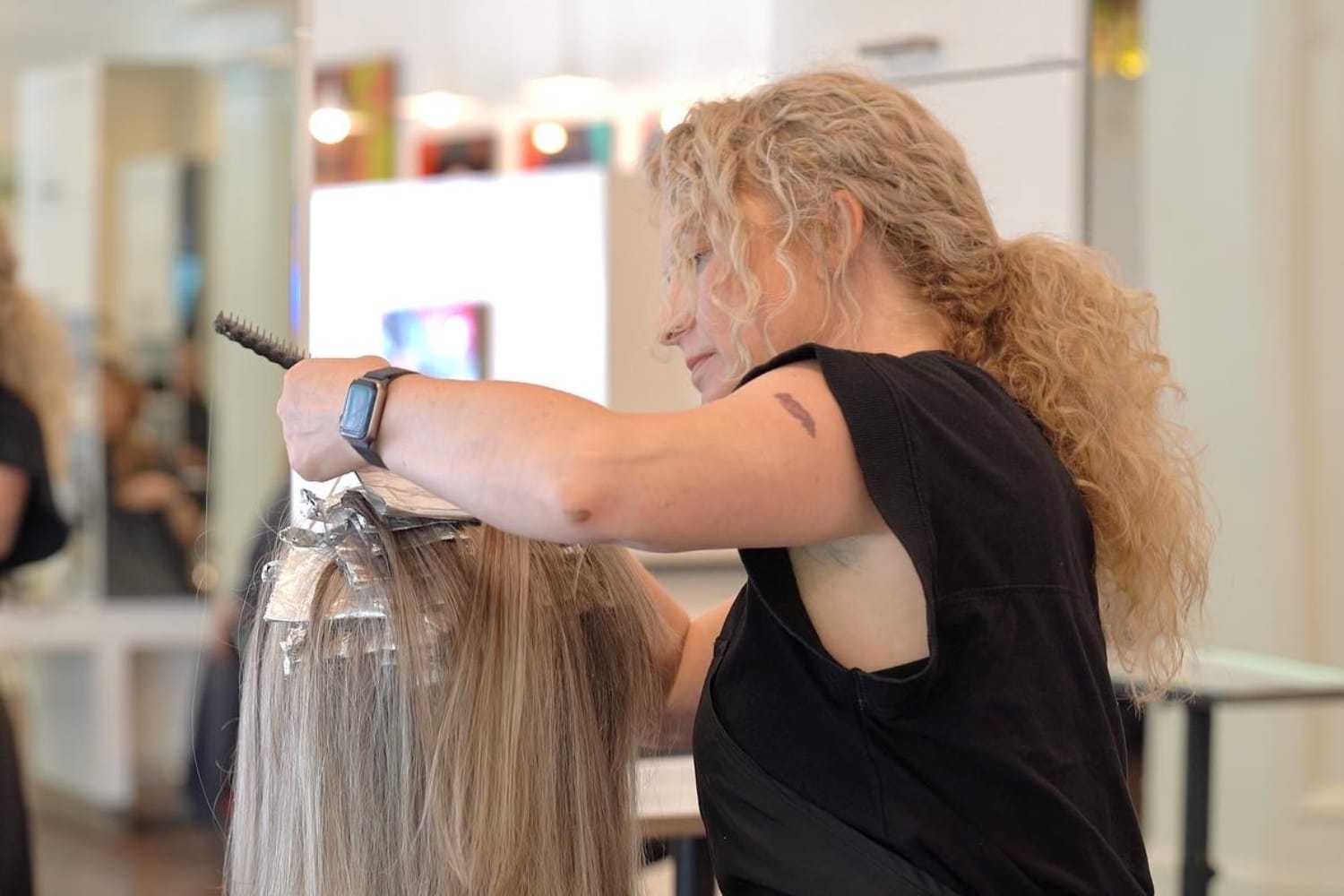 Hair stylist applying foils and dye to a client's hair in a salon.