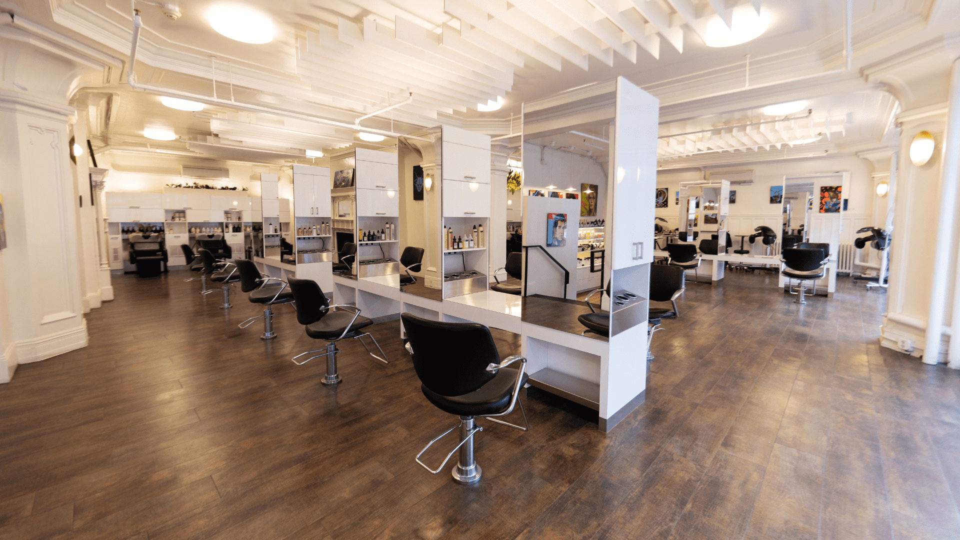 Modern hair salon with stylish black chairs and mirrors, featuring bright lighting.