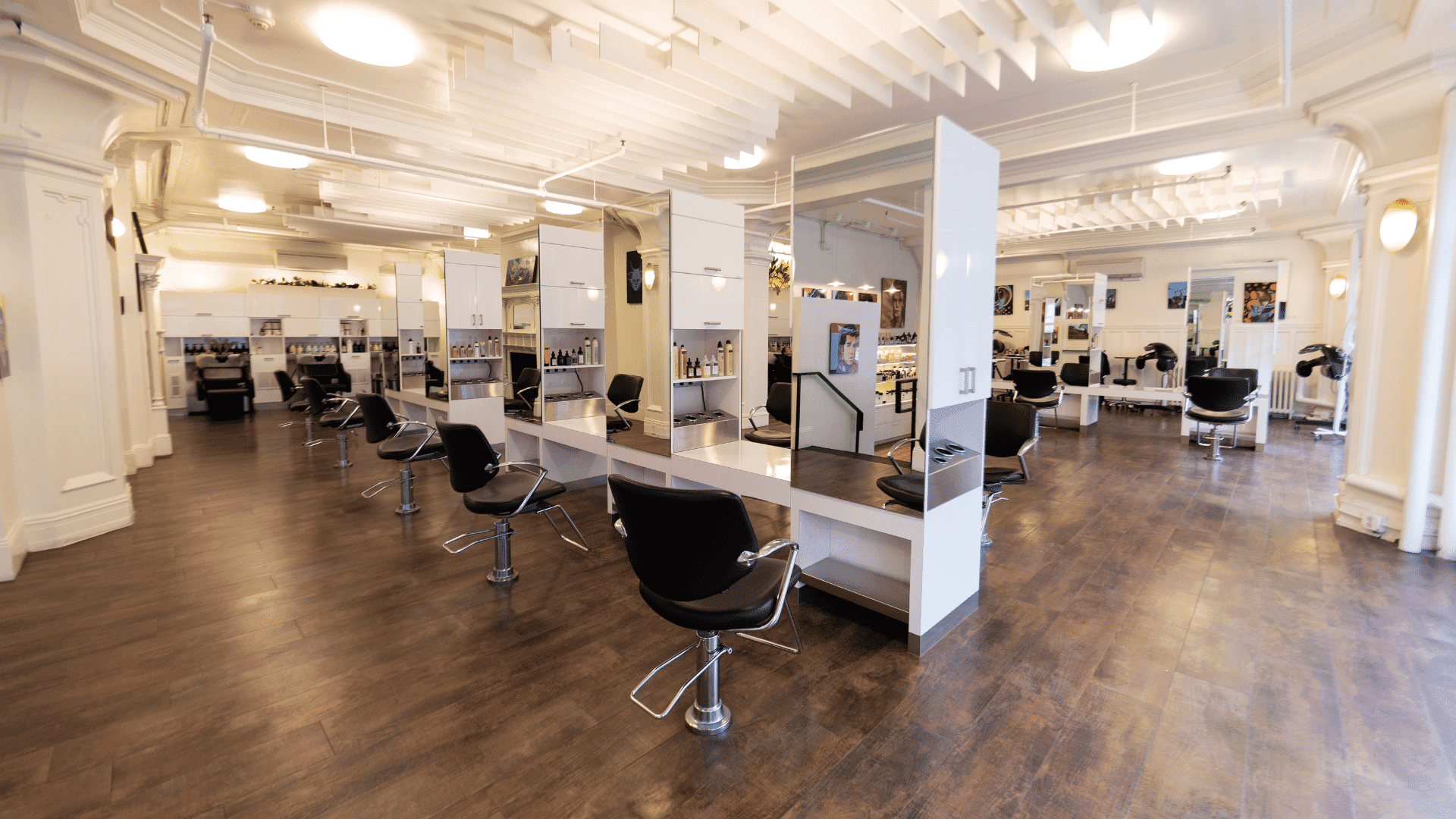 Modern hair salon with stylish black chairs and mirrors, featuring bright lighting.